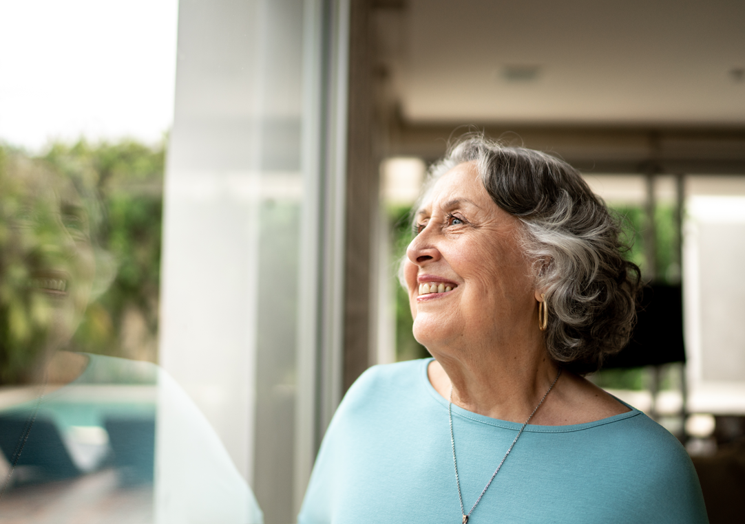Persona gran observant l'exterior per la finestra